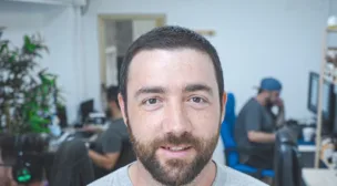 Hombre joven caucásico con barba mirando a cámara en un ambiente gamer