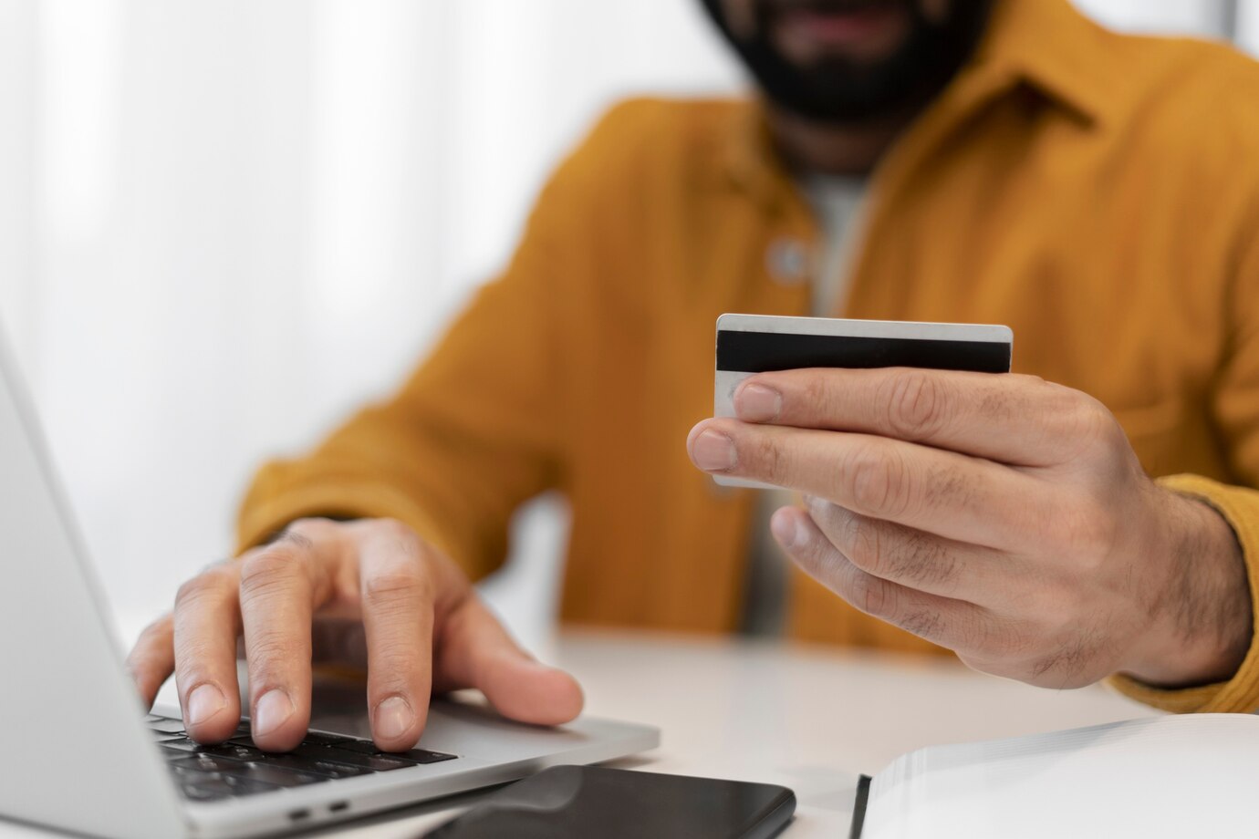 Hombre irreconocible con una tarjeta bancaria en mano a punto de hacer un depósito en un casino online desde su computadora